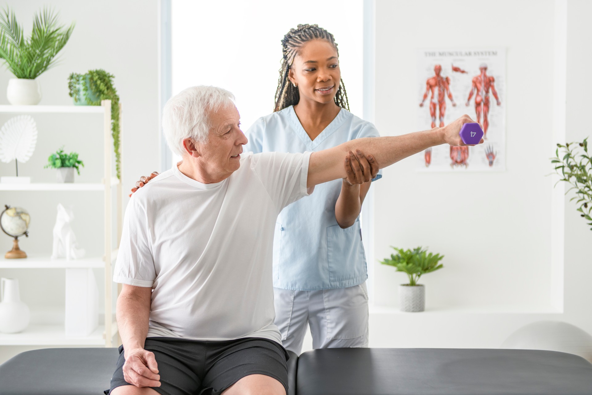 Black physiotherapist helping senior man with in clinic. Elderly man undergoing physiotherapy treatment for injury